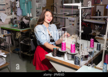 Bella curva modello femminile immaginato come pinup seamstresses presso un laboratorio di abbigliamento Foto Stock