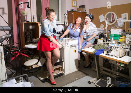 Bella curva modelli femmina immaginato come pinup seamstresses presso un laboratorio di abbigliamento Foto Stock