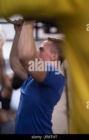 Fitness uomo bello fare immersione esercizio utilizzando anelli in palestra Foto Stock
