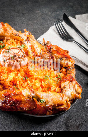 West African National cucina. Riso Jollof con grigliate di ali di pollo e banane fritte banane da cuocere.sulla pietra grigia tabella. Spazio di copia Foto Stock