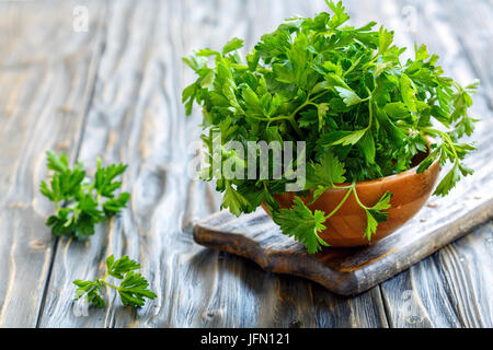 Prezzemolo fresco di foglie in una ciotola di legno. Foto Stock