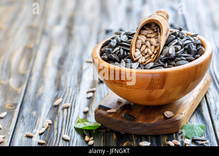 Cucchiaio di legno con semi puliti nella ciotola con i semi di girasole. Foto Stock
