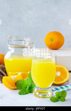 Un rinfrescante drink estivo con succo di arancia, succo di arance fresche e menta su una pietra grigio ardesia o sfondo. Foto Stock