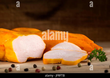 Close up di pollo pastrami con grani di pepe e prezzemolo su legno sfondo rustico Foto Stock