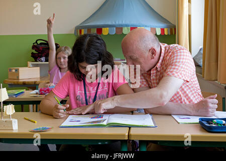 La scuola primaria ragazza con accompagnatore della scuola presso la scuola primaria Foto Stock