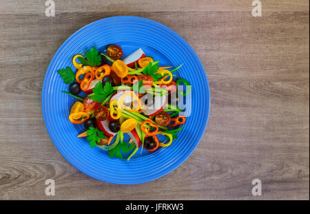 Insalata di verdure fresche con lattuga, pomodori, cetrioli e carote in vetro su sfondo di legno. Foto Stock