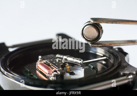 Sostituire la batteria in un orologio da polso. Close-up di pinzette Immissione sulla batteria orologio da polso Foto Stock