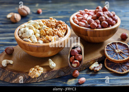 Noci,anacardi, nocciole e arachidi in ciotole di legno. Foto Stock