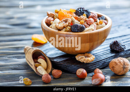 Ciotola con la frutta secca e il mix di dadi su un vecchio tavolo di legno, fuoco selettivo. Foto Stock