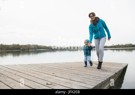 Madre e figlio camminando sul pontile in legno sopra il lago Foto Stock