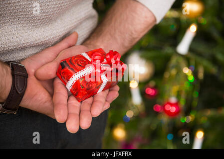 Uomo che tiene dietro di sé il regalo di natale Foto Stock