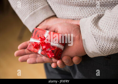 Uomo che tiene dietro di sé il regalo di natale Foto Stock