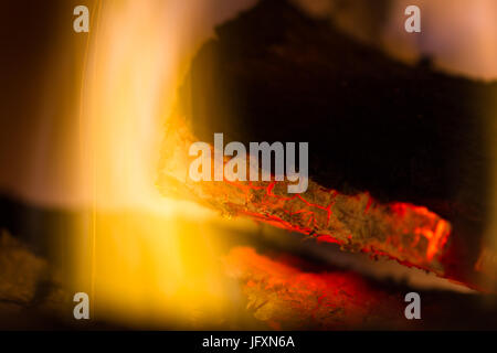 Close up rosso incandescente tizzi e fiamme su un lotto nel caminetto Foto Stock