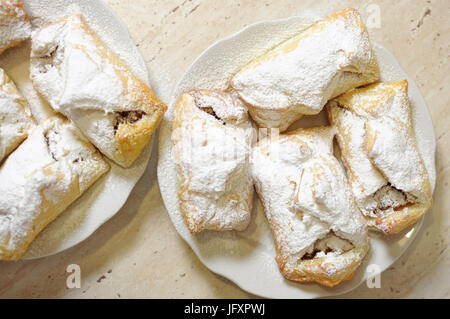 Bignè con marmellata di mele e zucchero in polvere su due piastre bianche vicino fino Foto Stock