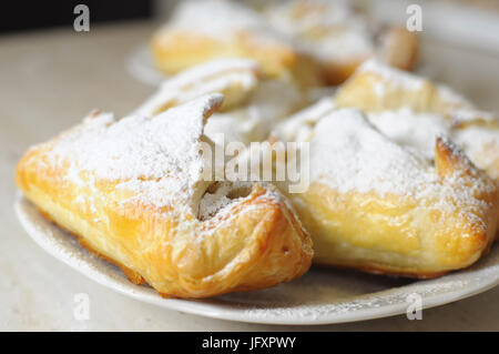 Bignè con marmellata di mele e zucchero in polvere su una piastra bianca close up Foto Stock