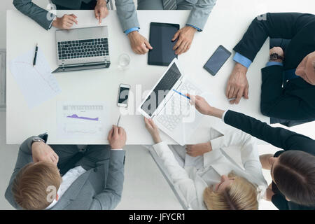 La gente di affari il brainstorming alla scrivania in ufficio, analizzando le relazioni finanziarie e di lavorare con i computer portatili e tablet Foto Stock