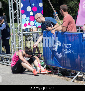 Southampton, Regno Unito. 02Luglio, 2017. Giovane atleta, che soffrono di esaurimento di calore, è di aiuto da parte degli astanti al traguardo della corsa per la vita. Questa gara annuale è gestito da donne per raccogliere fondi per la ricerca sul cancro. Credito: Jane Rix/Alamy Live News Foto Stock