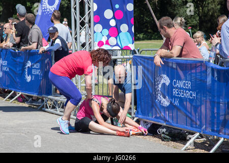 Southampton, Regno Unito. 02Luglio, 2017. Giovane atleta, che soffrono di esaurimento di calore, è di aiuto da parte degli astanti al traguardo della corsa per la vita. Questa gara annuale è gestito da donne per raccogliere fondi per la ricerca sul cancro. Credito: Jane Rix/Alamy Live News Foto Stock