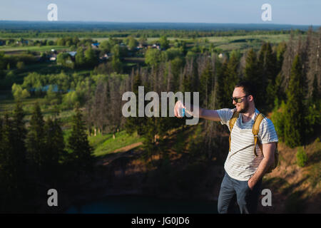 Giovane uomo elegante con la barba indossando occhiali da sole rende selfie sulle pareti del canyon Foto Stock