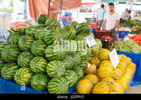 Un uomo attende i clienti sul suo mercato bancarella vendendo i meloni e verdure, Alanya, Turchia Foto Stock