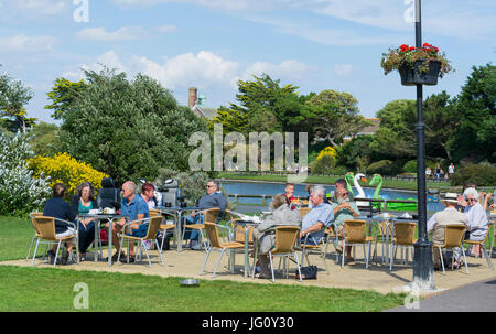 La gente seduta al di fuori di un bar nel Parco Mewsbrook, Littlehampton, West Sussex, in Inghilterra, Regno Unito. Foto Stock
