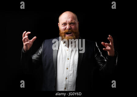 Urlando uomo con mani tese con zenzero barba e baffi sul vuoto sullo sfondo di felce Foto Stock