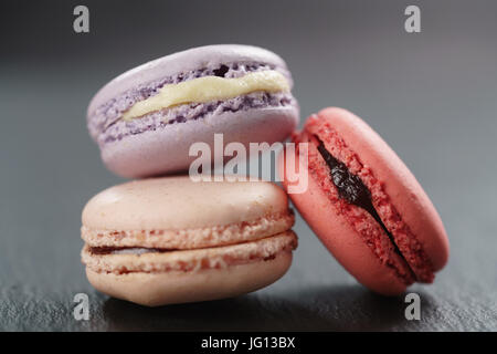 Tre mescolati macarons sulla scheda di ardesia, primo piano Foto Stock