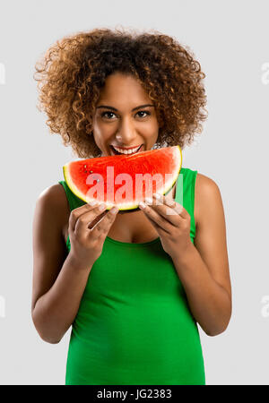 Bella americano africano donna olding e mangiare un frutto di cocomero Foto Stock