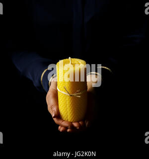 Black Mania. mani femminili isolati su sfondo nero che mostra una candela Foto Stock