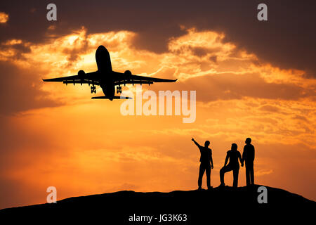 Il paesaggio con le sagome di un uomo in piedi puntando il dito sul passeggero aereo vola nel cielo colorato e i suoi amici sul picco di montagna a Foto Stock