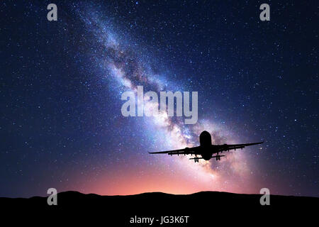 Via Lattea e silhouette di un aeroplano. Paesaggio con aereo passeggeri vola nel cielo stellato di notte. Sfondo spazio. Aereo commerciale Foto Stock