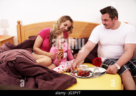 La prima colazione a letto con la famiglia felice Foto Stock