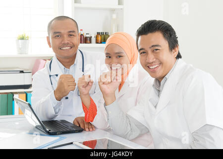 Il team medico di celebrare il successo in ufficio dell'ospedale. Sud-est asiatico musulmani medici e infermieri. Foto Stock