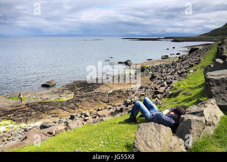 L'uomo rilassante sulla spiaggia Staffin, sull'Isola di Skye in Scozia Foto Stock