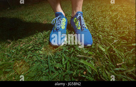 L'uomo stand in scarpe da jogging sul prato verde dello sfondo. Primo piano della runner gambe Foto Stock