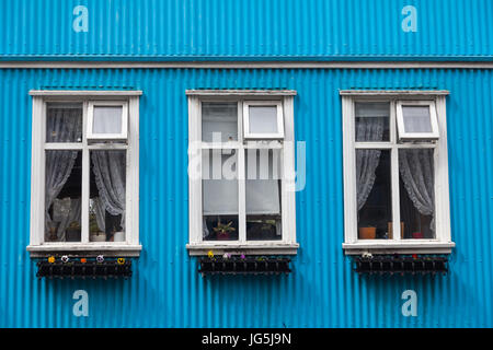 Tre finestre bianche sul lato di una casa blu in Reykjavik Foto Stock