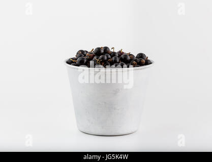 Ribes nero e bacche impilati in ceramica e alluminio bowl, isolati su sfondo bianco, freschi Frutti vegano concept Foto Stock