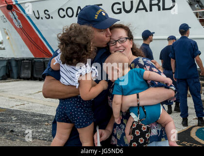 Un membro di equipaggio a bordo del guardacoste Venturous riunisce con la sua famiglia Sabato, 1 Luglio 2017 dopo il ritorno a casa a San Pietroburgo, in Florida. La taglierina restituito dopo un 60-giorno di formazione e di applicazione della legge patrol nel mid-Oceano Atlantico a sostegno dell'operazione Ocean Hunter. (U.S. Coast Guard foto di Sottufficiali di prima classe Michael De NYSE) Foto Stock