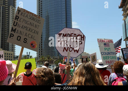 "Impeach Trump Ora' e altri segni tenuto sopra le teste dei manifestanti in l'impeachment Marzo a San Diego, CA il 2 luglio mentre si spostano lungo la strada. Foto Stock