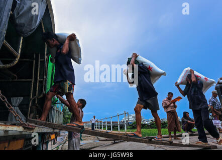 Lavoratori di scarico delle merci dai battelli su In attesa di camion a un dock a Yangon, Myanmar Foto Stock