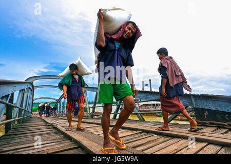 Lavoratori di scarico delle merci dai battelli su In attesa di camion a un dock a Yangon, Myanmar Foto Stock