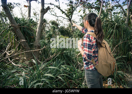Vista posteriore foto della bella giovane donna escursionista camminando sul parco naturale e del paesaggio di puntamento condivisione per amico in vacanza estiva. Foto Stock