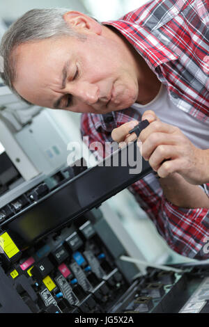 Repairman mettere la cartuccia di inchiostro nella stampante Foto Stock