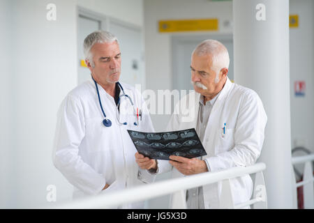 Due esperti medici di sesso maschile a discutere di raggi x in ospedale corridorb Foto Stock