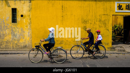 Una donna vietnamita vanno in bicicletta in una strada a Hoi An, Vietnam Foto Stock