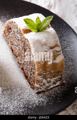 Pezzo di strudel con semi di papavero e dadi macro su di una piastra verticale. Foto Stock