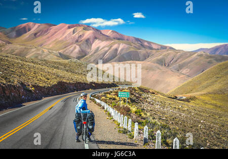 Donna ciclismo su strada vuota nella parte remota del nord ovest Argentina Foto Stock