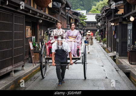 Geisha in abbigliamento tradizionale utilizzando tradizionale giapponese del trasporto pubblico, la potenza umana risciò. Takayama e Giappone. Foto Stock