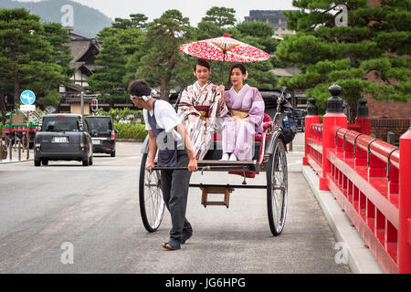 Geisha in abbigliamento tradizionale utilizzando tradizionale giapponese del trasporto pubblico, la potenza umana risciò. Takayama e Giappone. Foto Stock