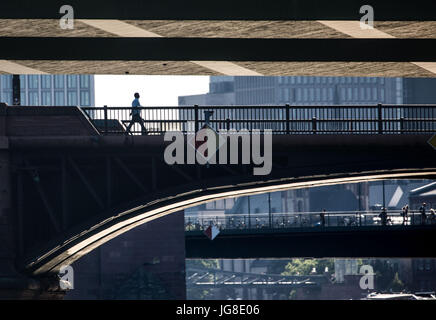 Un uomo cammina attraverso la Ignatz Bubis bridge durante la serata a Francoforte sul Meno, Germania, 26 giugno 2017. Una parte del ponte Floesser può essere visto sulla parte superiore, la Alte Bruecke ("Old Bridge") sull'boggom e il Eiserner Steg ponte nella distanza. Foto: Frank Rumpenhorst/dpa Foto Stock